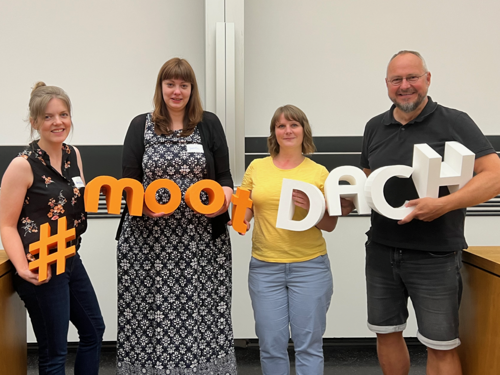 Hier ist unser Team aus Wuppertal zu auf der Moodlemoot zu sehen. Sie tragen die die Buchstaben des Hash-tags zur Veranstaltung:  # m o o t D A CH 